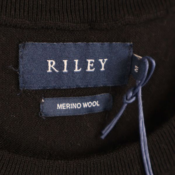 Närbild på blå Riley-tag och merinoetikett vid halsringningen