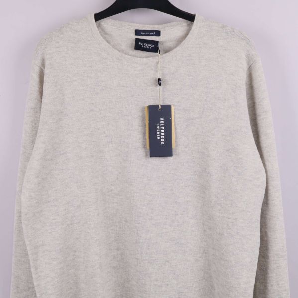 Närbild på beige tröjas framsida och etikett