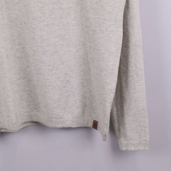 Närbild på nederkant och söm till beige tröja