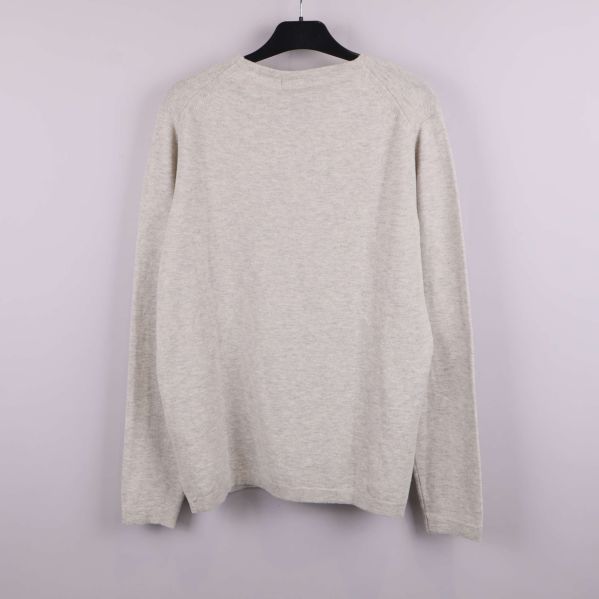 Baksida av beige långärmad tröja på galge