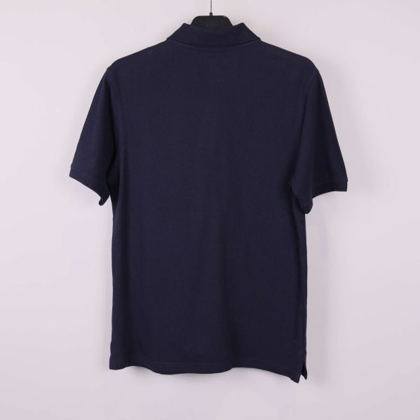 Mörkblå pikétröja bakifrån mot ljus bakgrund