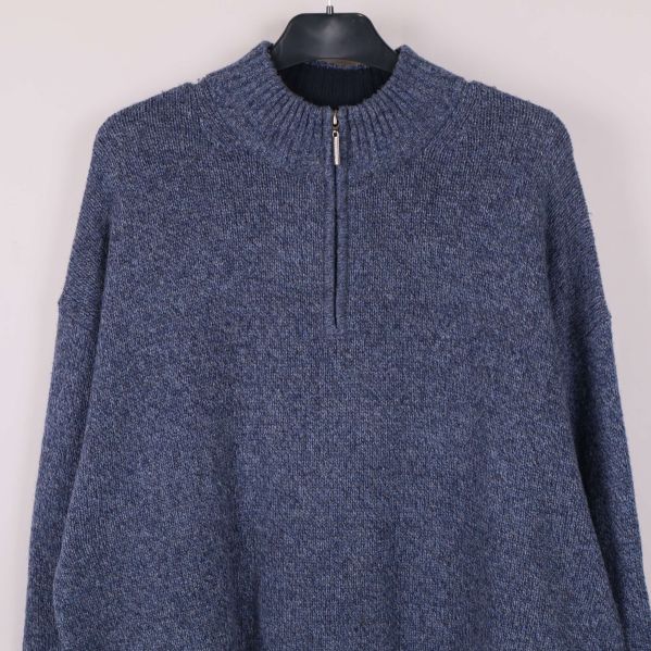 Överkroppsdetalj på blå stickad tröja med dragkedja