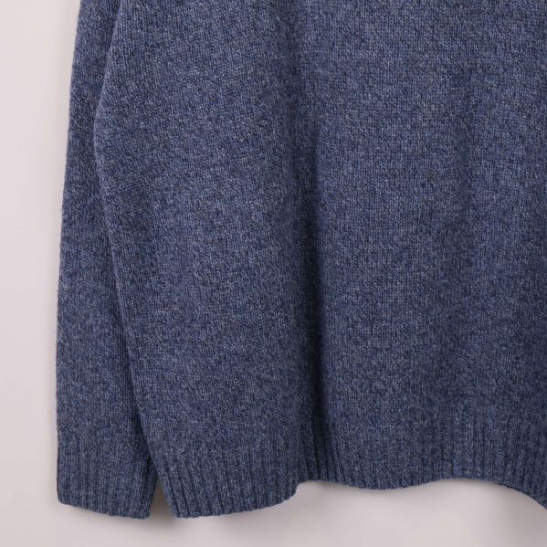 Nedre del av blå stickad tröja med ribbade muddar