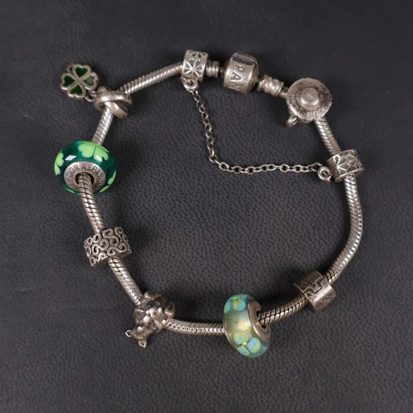 Närbild på charmarmbandets berlocker och glaspärlor