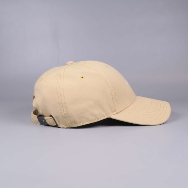 Beige keps sedd från sidan mot grå bakgrund