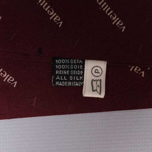 Materialetikett med information om 100% siden och italienskt ursprung