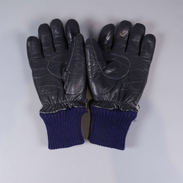 Baksida på två svarta handskar med blå muddar syns