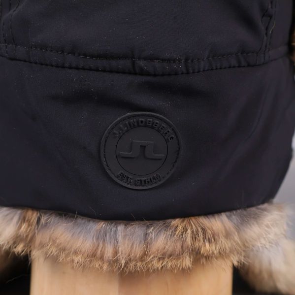 Närbild av JL-märke på svart mössa med fuskpäls
