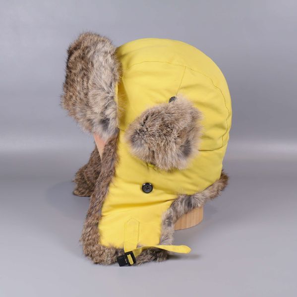 Sida av gul vintermössa med pälsdetaljer och knäppning