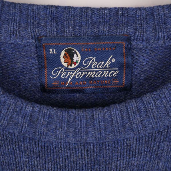 Närbild på Peak Performance etikett i halsen på blå tröja