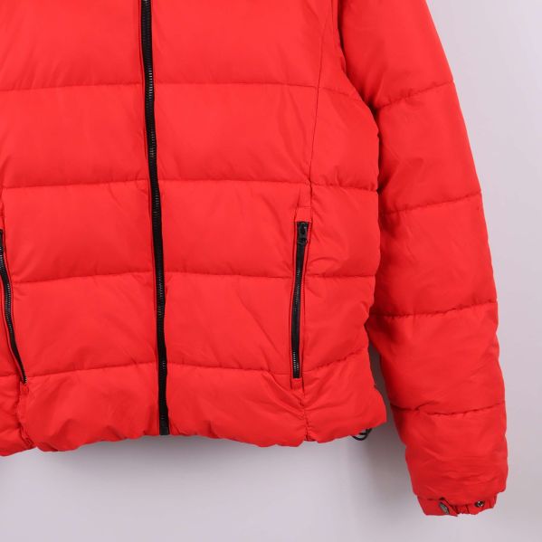 Närbild på dragkedjor och fickor på röd jacka