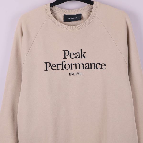 Närbild av logotypen Peak Performance broderad på bröstet