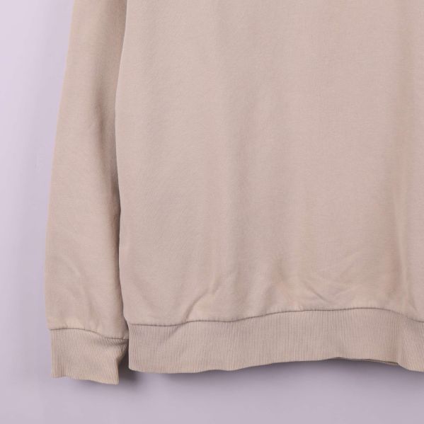 Närbild på nederkant och mudd på beige sweatshirt