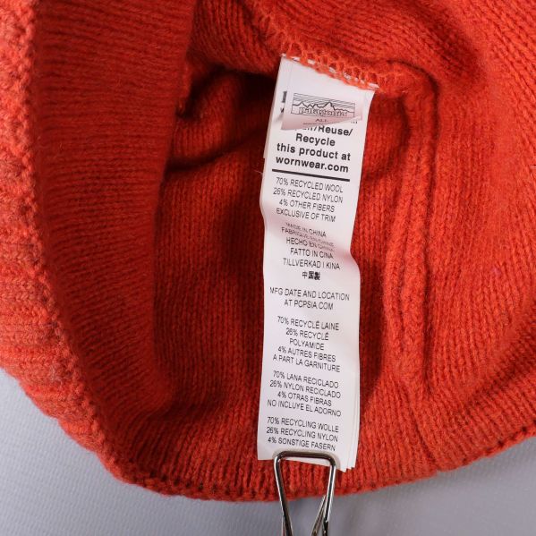 Materialetikett invändigt i orange stickad mössa