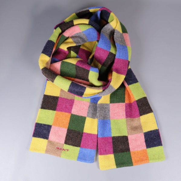 Färgglad rutig halsduk upplagd i en ring på grå bakgrund