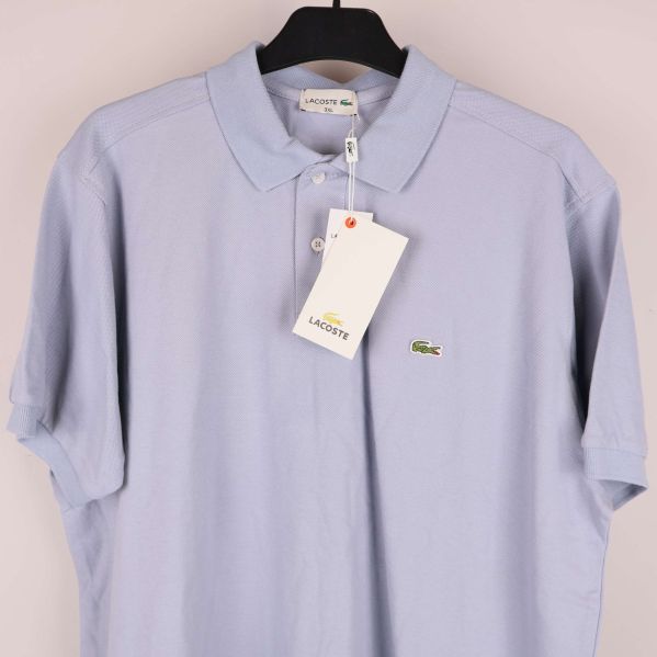 Ljusblå pikétröja med hängande tagg och logotyp