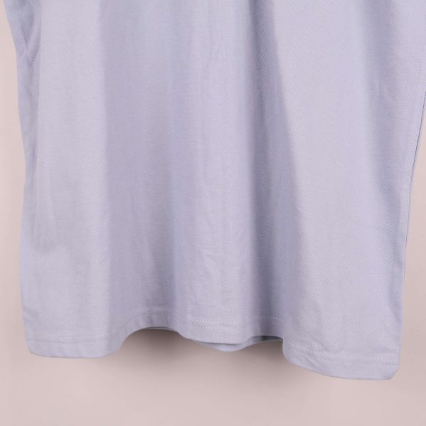 Nedre del av ljusblå pikétröjans framsida