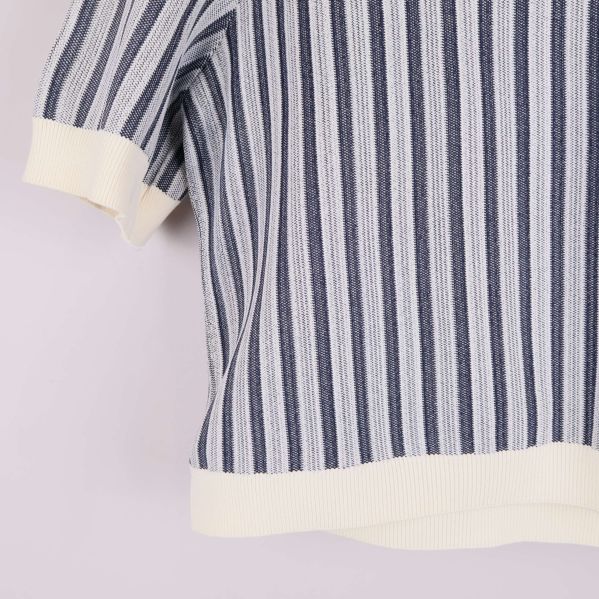 Närbild på nederkant och ärmslut med vita ribbade detaljer