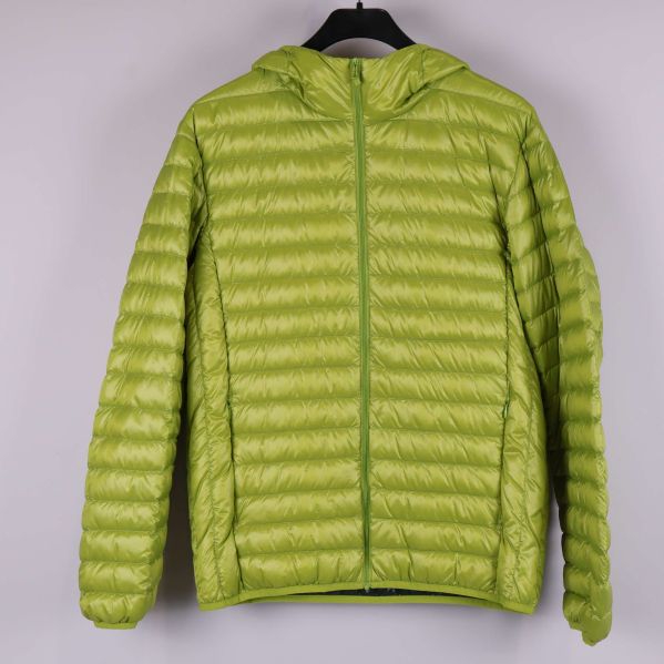 Framsidan av quiltad grön jacka med huva och dragkedja