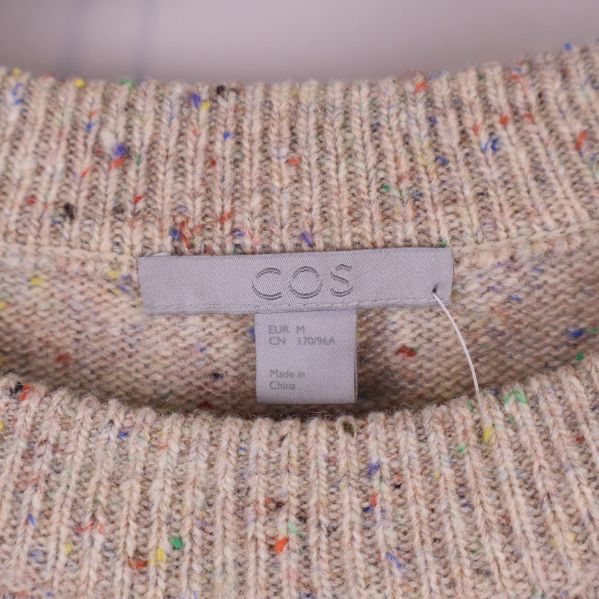 Närbild på cos logotyp i halsen på tröjan