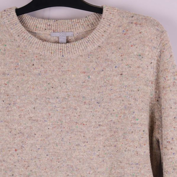 Närbild på halsringning och axel på beige melerad tröja