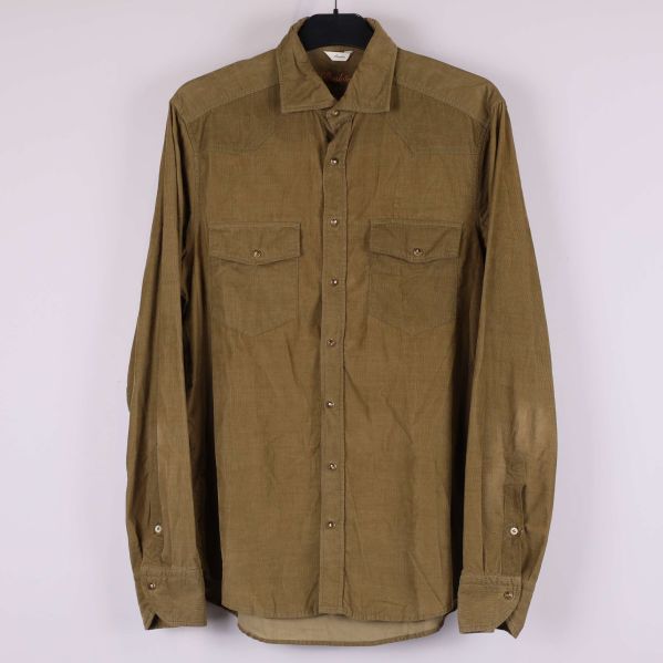 Manchesterskjorta i khaki med två bröstfickor hänger på en galge