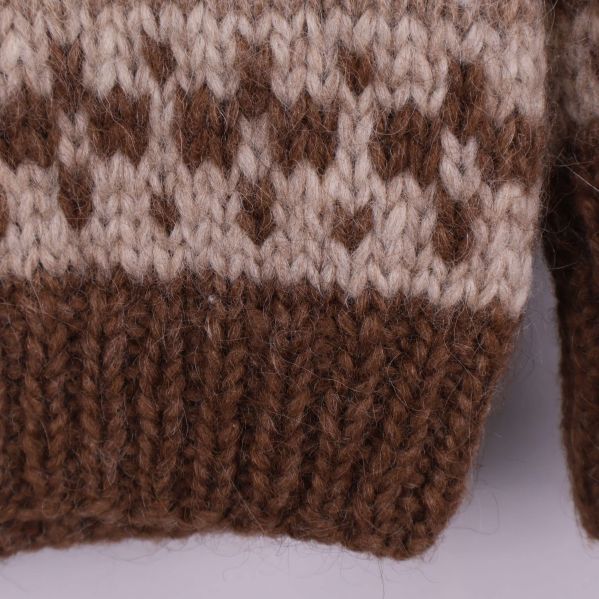 Närbild på grovstickad brun mudd på tröjan