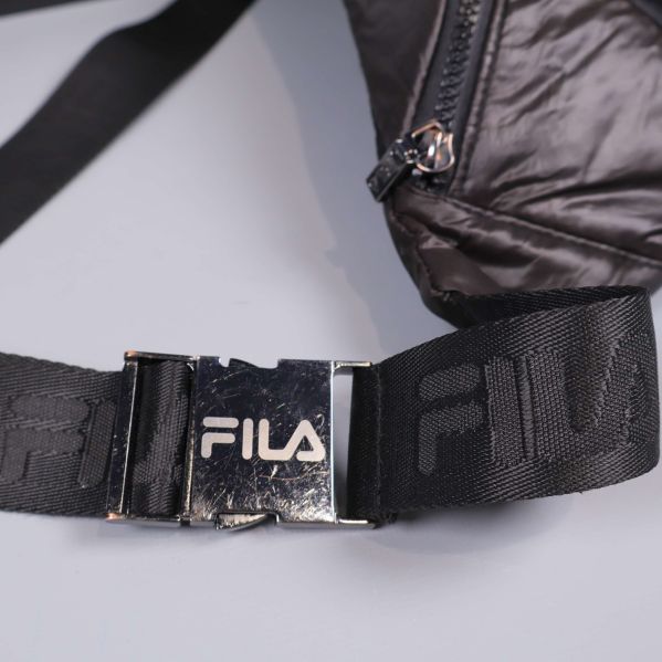 Metallspänne på svart rem med FILA-logotyp i fokus