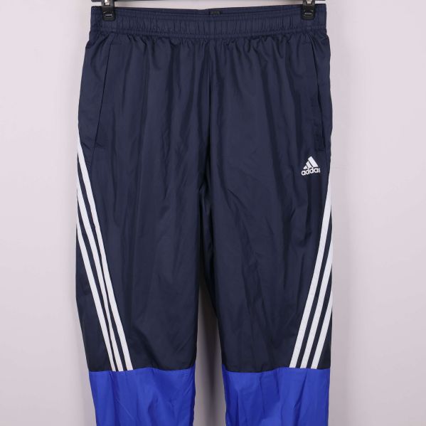 Närbild av träningsbyxor med adidas-logga och vita ränder