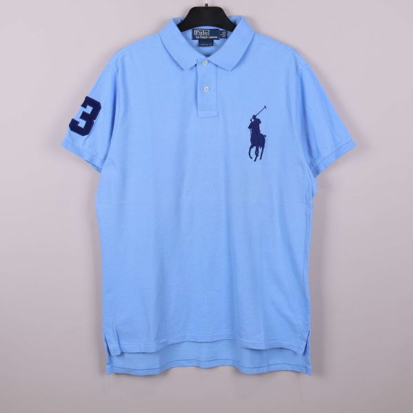 Ljusblå pikétröja med stor logotyp framtill