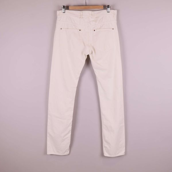 Baksida på vita jeans med två bakfickor upphängda på galge