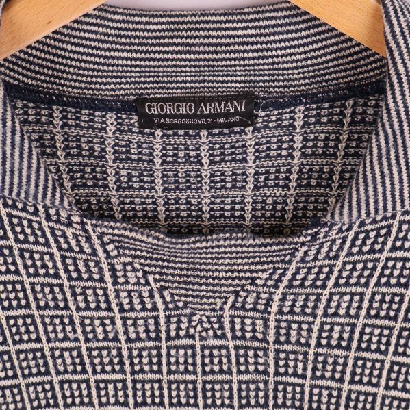 Närbild på krage och Giorgio Armani-märke i stickad tröja