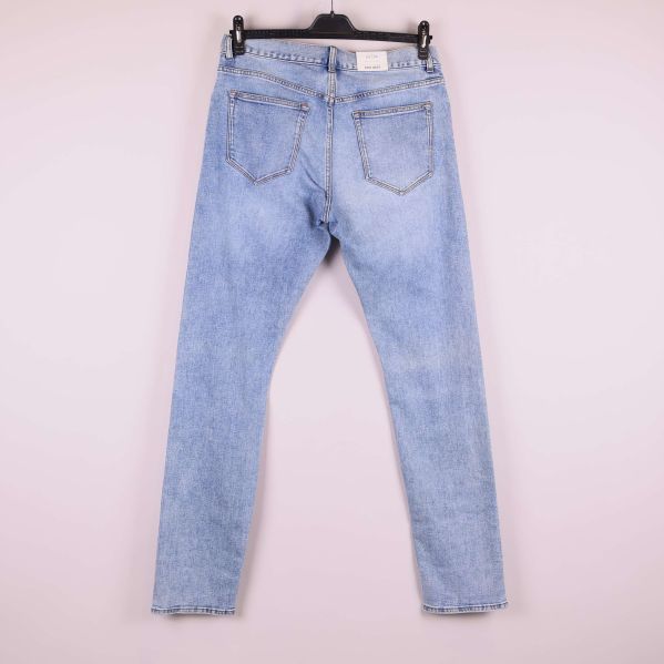 Jeans i ljus denim upphängda på galge, helbild bakifrån