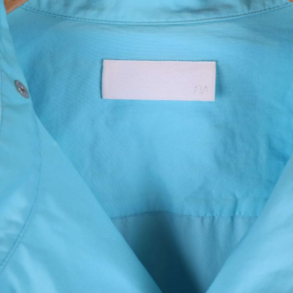 Närbild på etikett i nacken av ljusblå skjorta