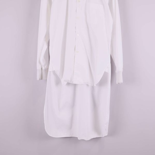 Nedre del av vit skjorta som visar förlängd design