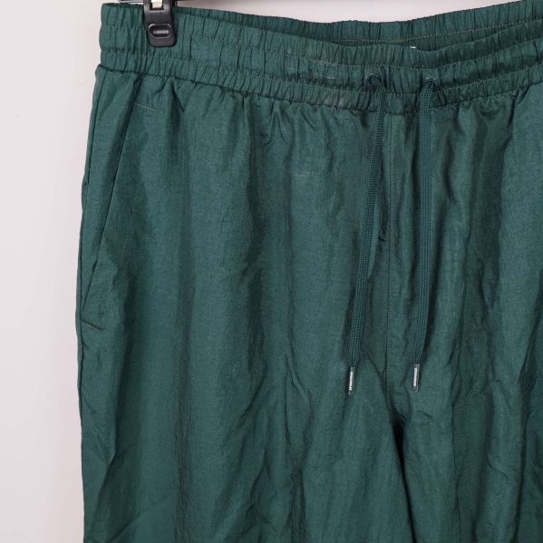 Midjedel med dragsko och fickdetalj på gröna byxor