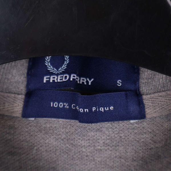 Närbild på etikett med Fred Perry och storlek S