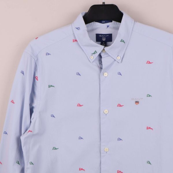 Detaljbild på skjortans bröst och krage med broderade flaggor