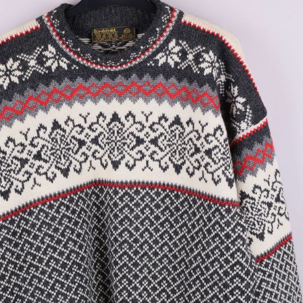 Närbild av tröjans överdel med snöflingemönster och röda detaljer