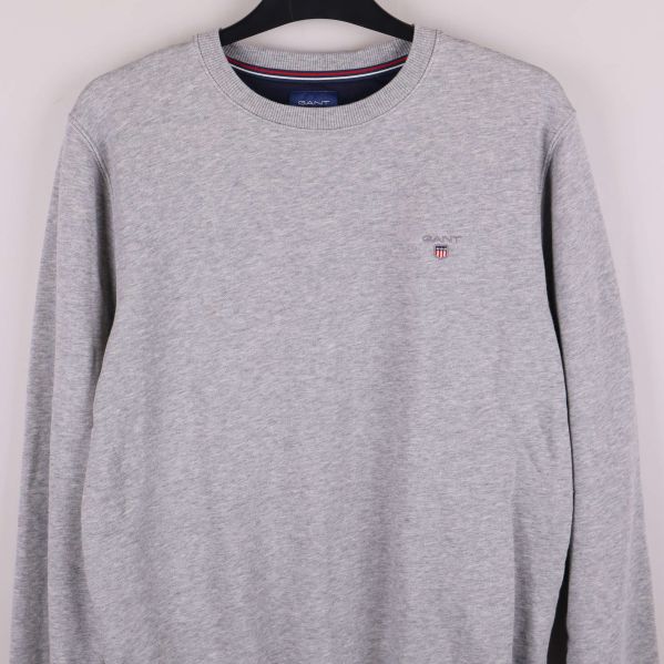 Närbild av grå sweatshirt med broderat emblem