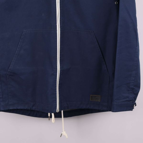 Närbild på jackans nedre framdel med ficka och logodetalj