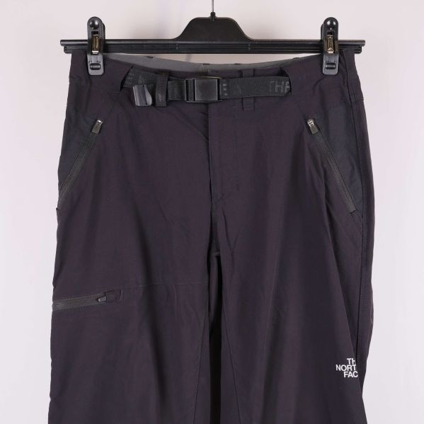 Övre del av mörka byxor med dragkedjor och bälte