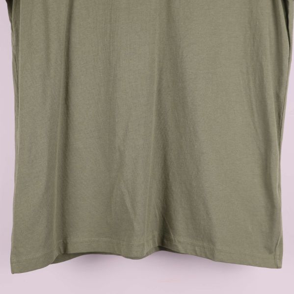 Detalj av nederkant och sidsöm på olivgrön t-shirt