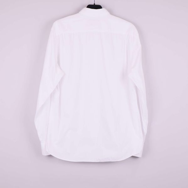Baksidan av vit skjorta hängande på galge utan synliga detaljer