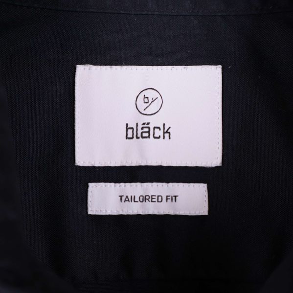 Närbild på etikett med texten by bläck tailored fit