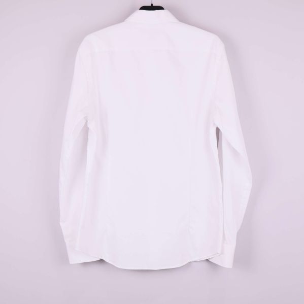 Baksidan på vit långärmad skjorta visas mot ljus bakgrund