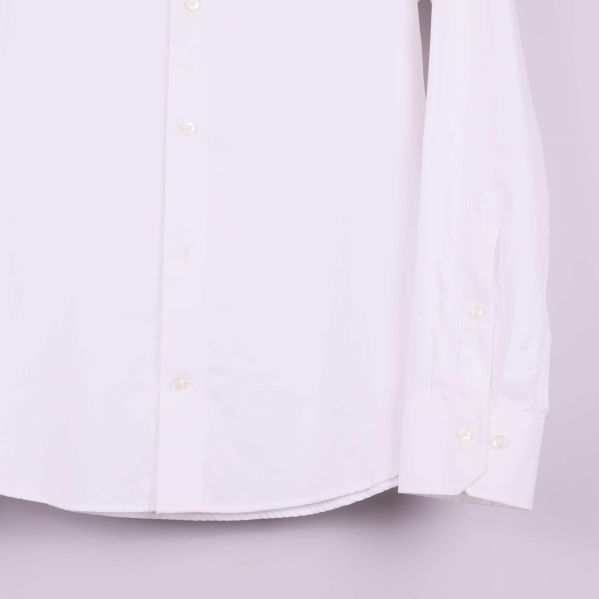 Ärmslut och knäppning på vit skjorta visas i detalj