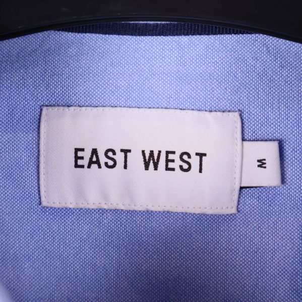 Närbild på etikett med texten East West och storlek M