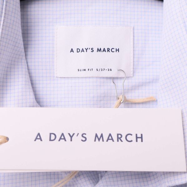 Närbild på varumärkestaggar från A Day's March i skjortkragen