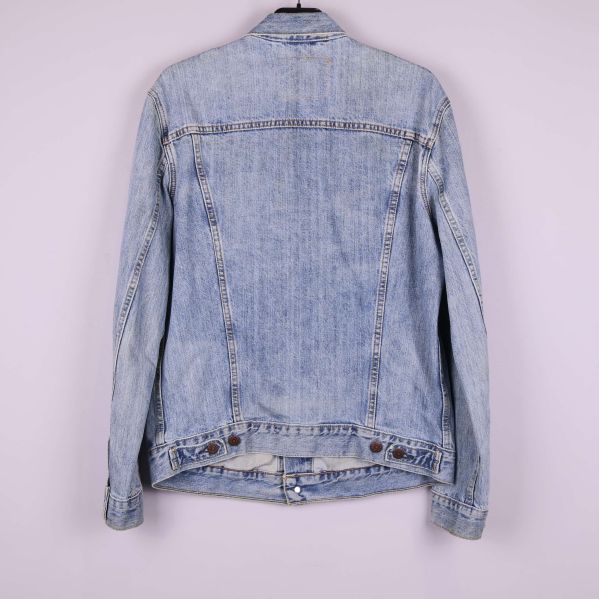 Baksidan av ljusblå jeansjacka mot ljus bakgrund